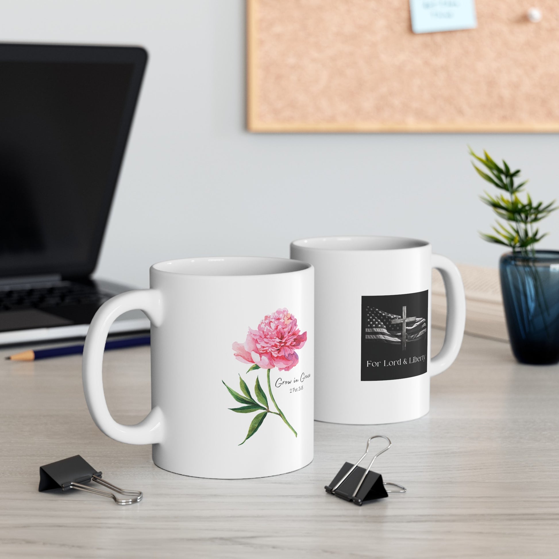 a white mug with a pink flower that says Grow in Grace 2 Peter 3:18 and another mug with the for lord and liberty logo that is sitting on a desk