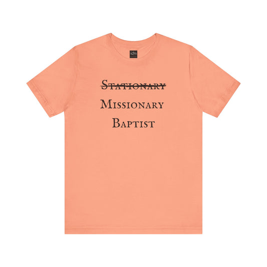 A sunset orange t-shirt with the word Stationary marked out with the words Missionary Baptist in bold