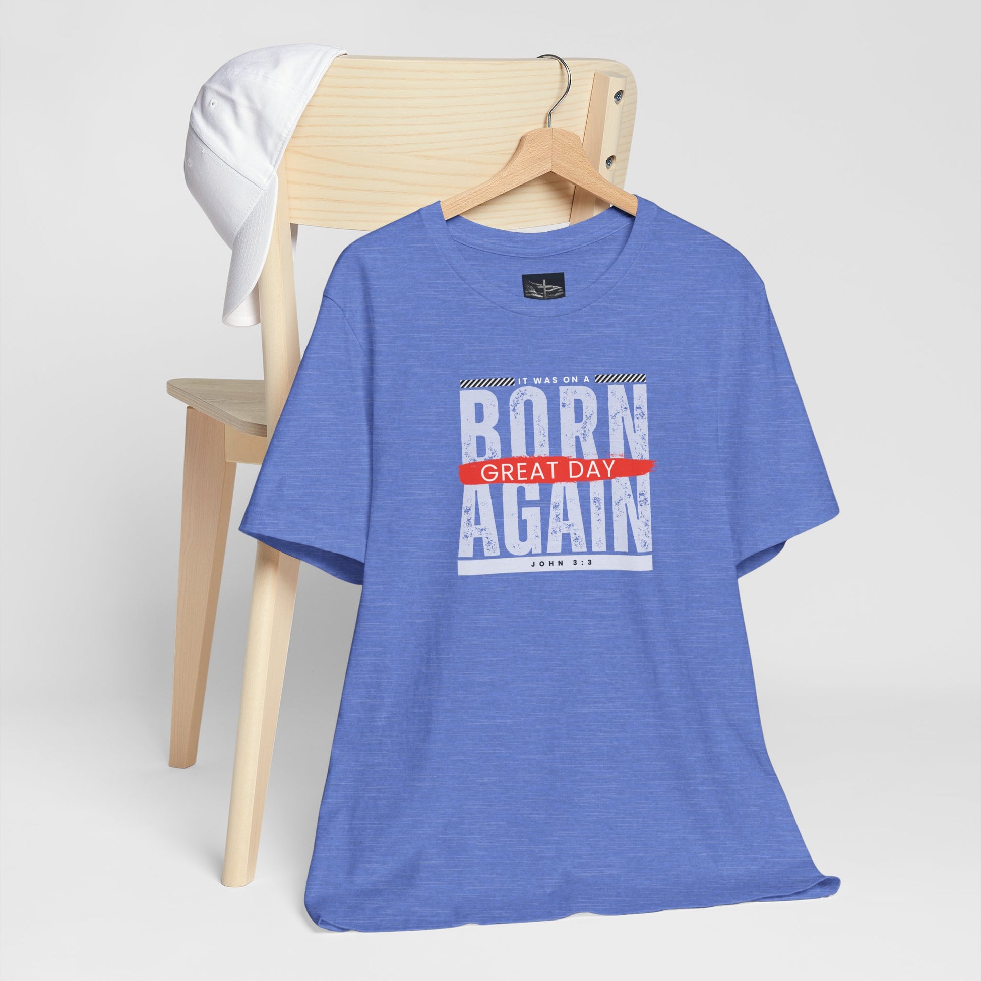 A blue t-shirt hanging on a wooden chair with the words Born Again it was on a Great Day with the scripture John 3:3