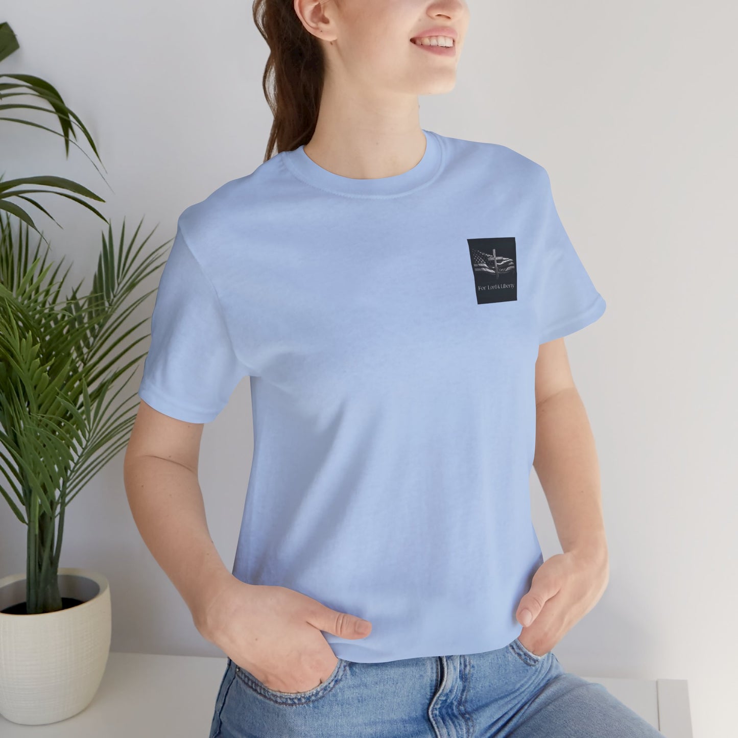 A female wearing a baby blue t-shirt the For Lord & Liberty logo on the front left pocket