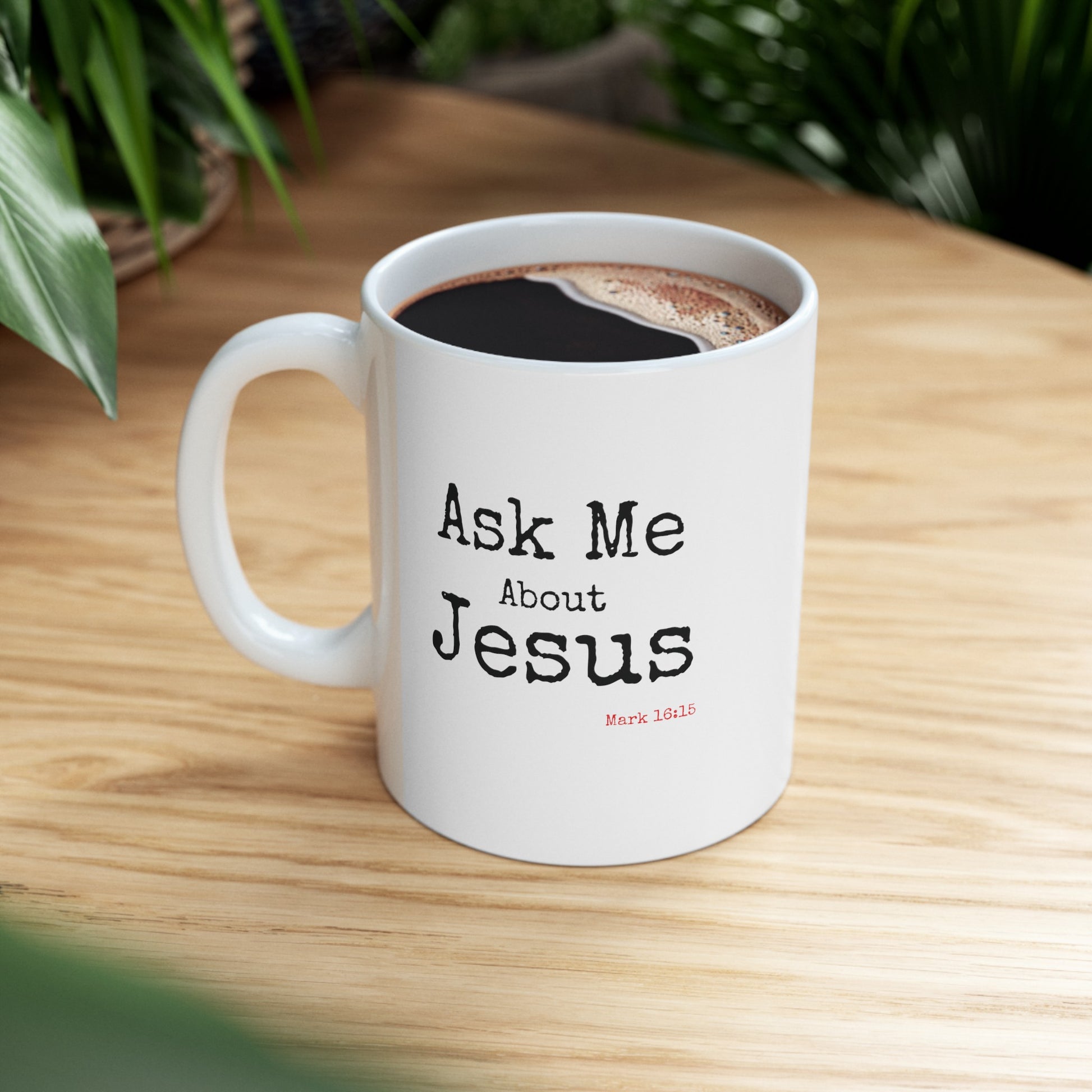 A white mug with the words Ask Me About Jesus Mark 16:15 written on the front of the mug