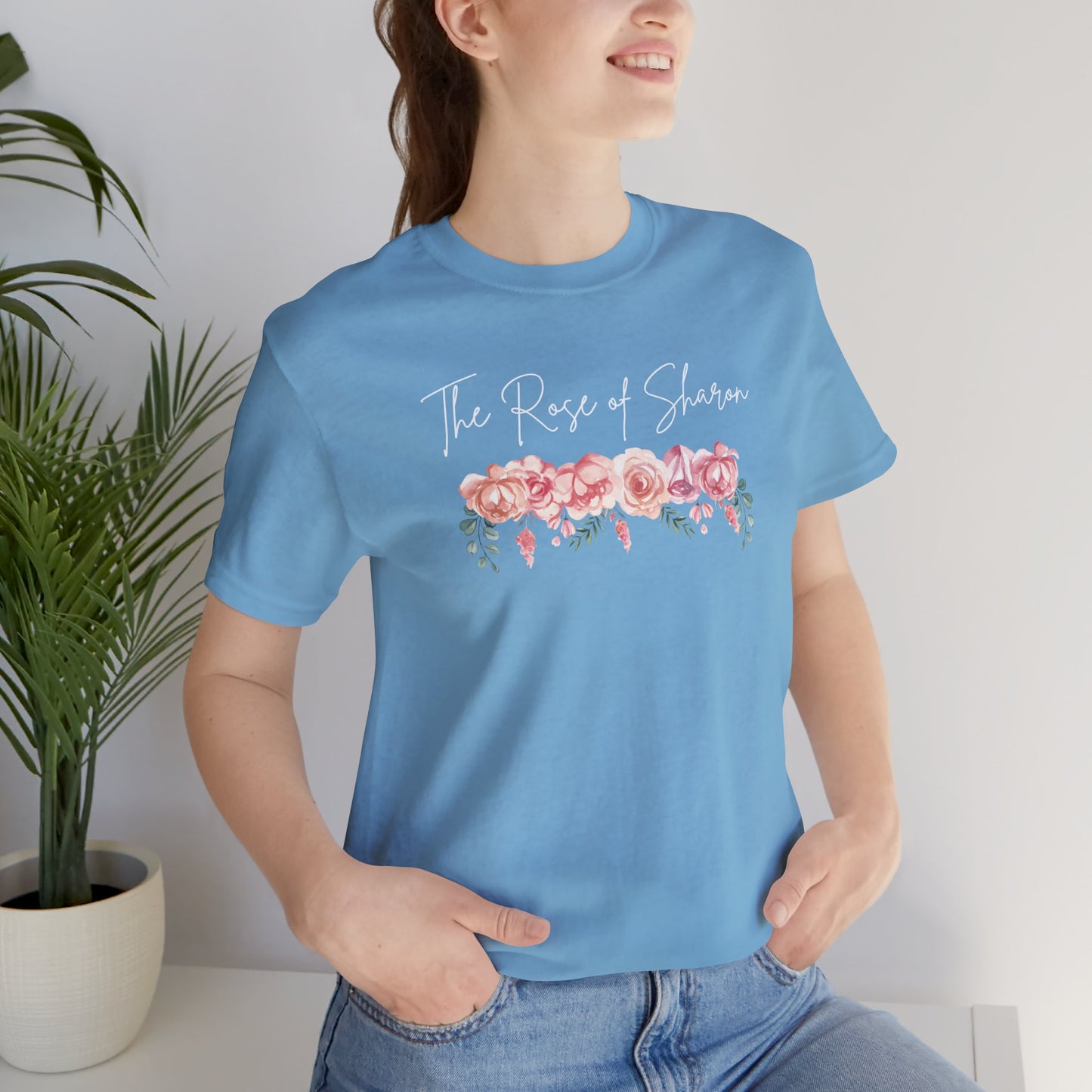 A female wearing a ocean blue t-shirt with the words Rose of Sharon with a picture of roses