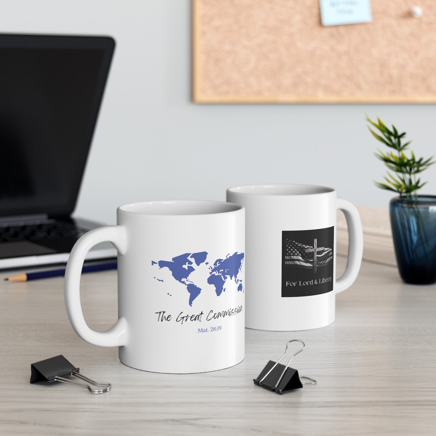 a white mug with the world and the words The Great Commission Mat. 28:19 and another mug with the for lord and liberty logo that is sitting on the desk