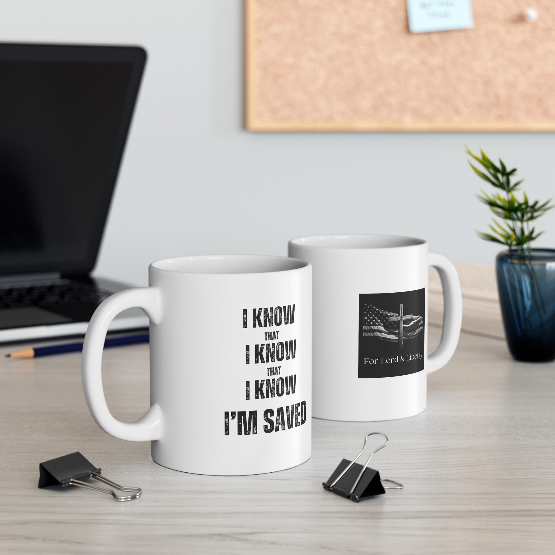 a white mug that says I Know that I Know that I Know I'm Saved and another mug with a for lord and liberty logo sitting on a desk