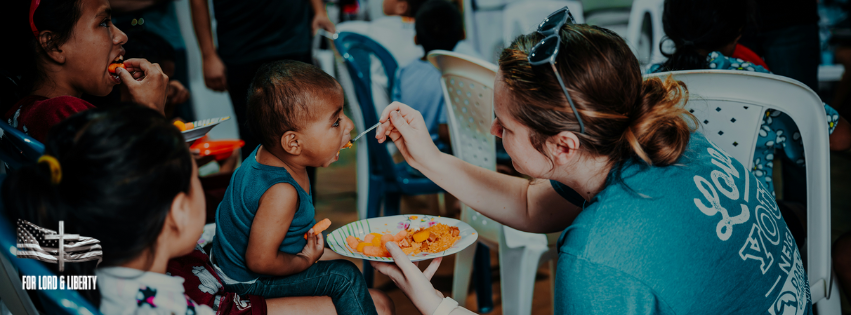 Volunteer feeding a young child at a community meal