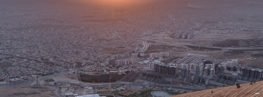 Aerial view of a sprawling city at sunrise, seen from a mountainside
