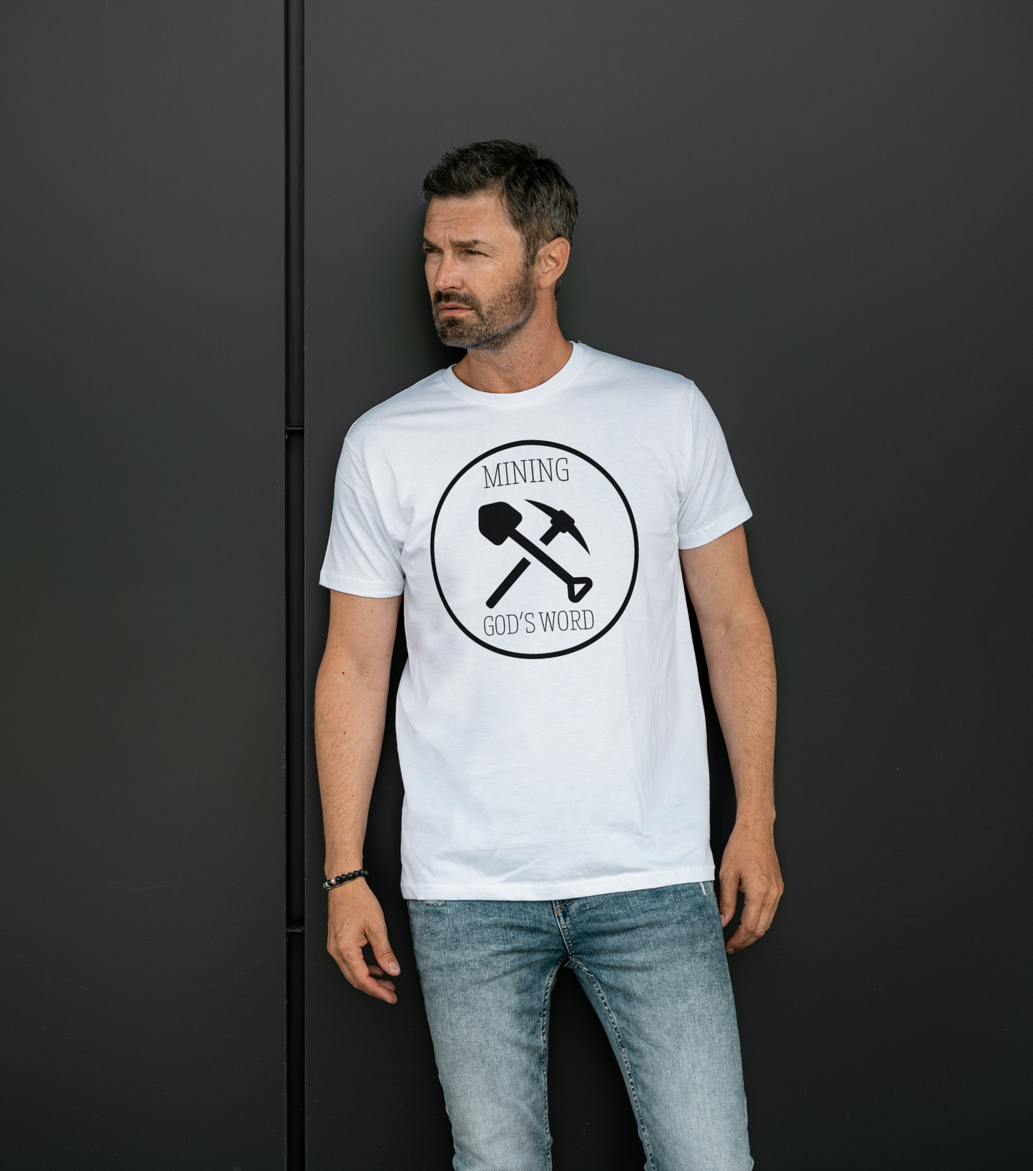 A male wearing a white t-shirt with the words Mining God's Word with a picture of a shovel and pick axe