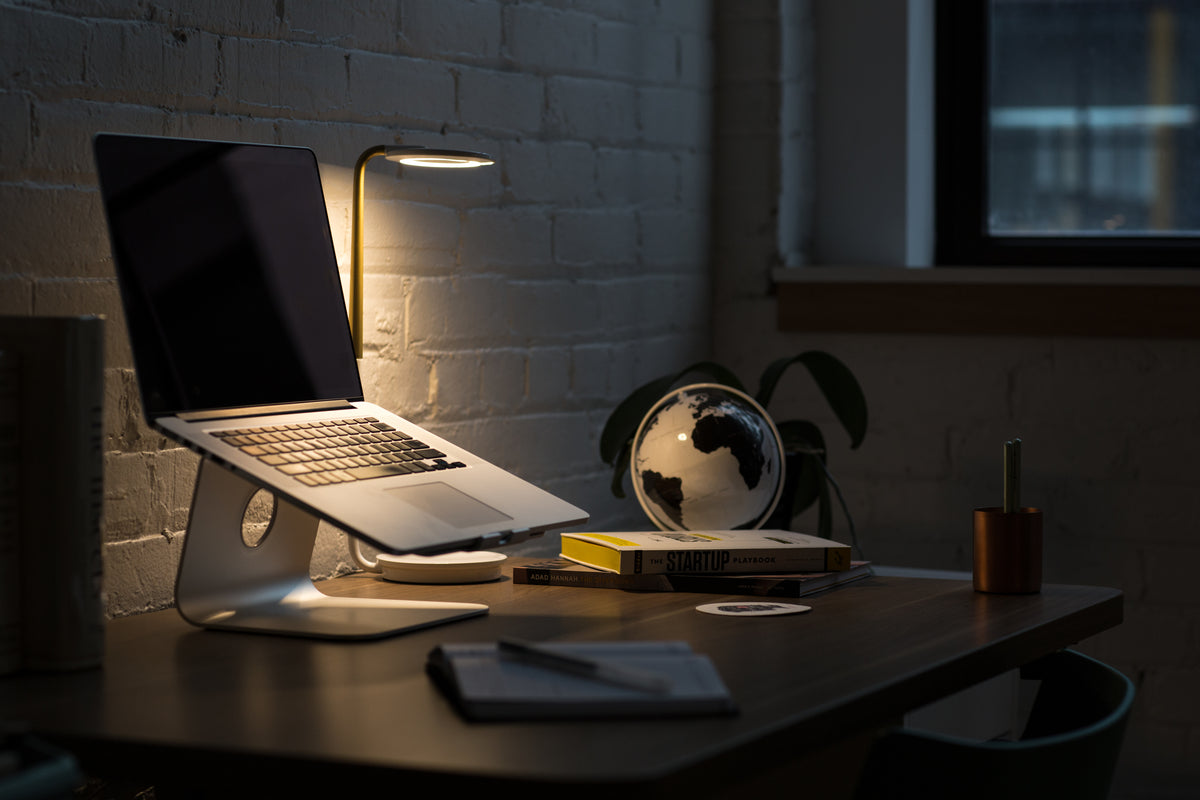 Laptop and desk lamp on a desk in a dark home office at night
